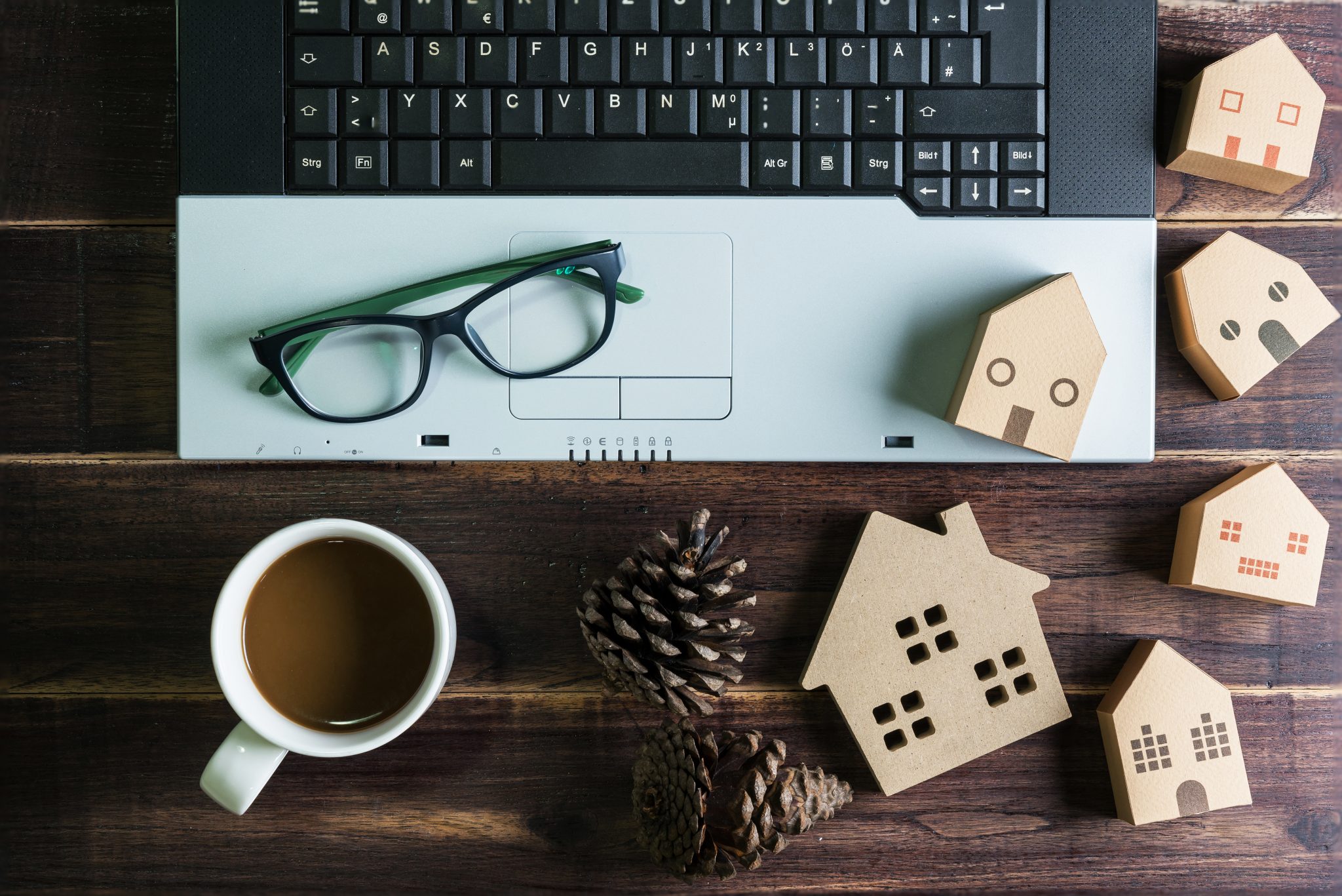 Vue de dessus d'objets de bureau avec un ordinateur portable, une tasse à café et une maison en bois